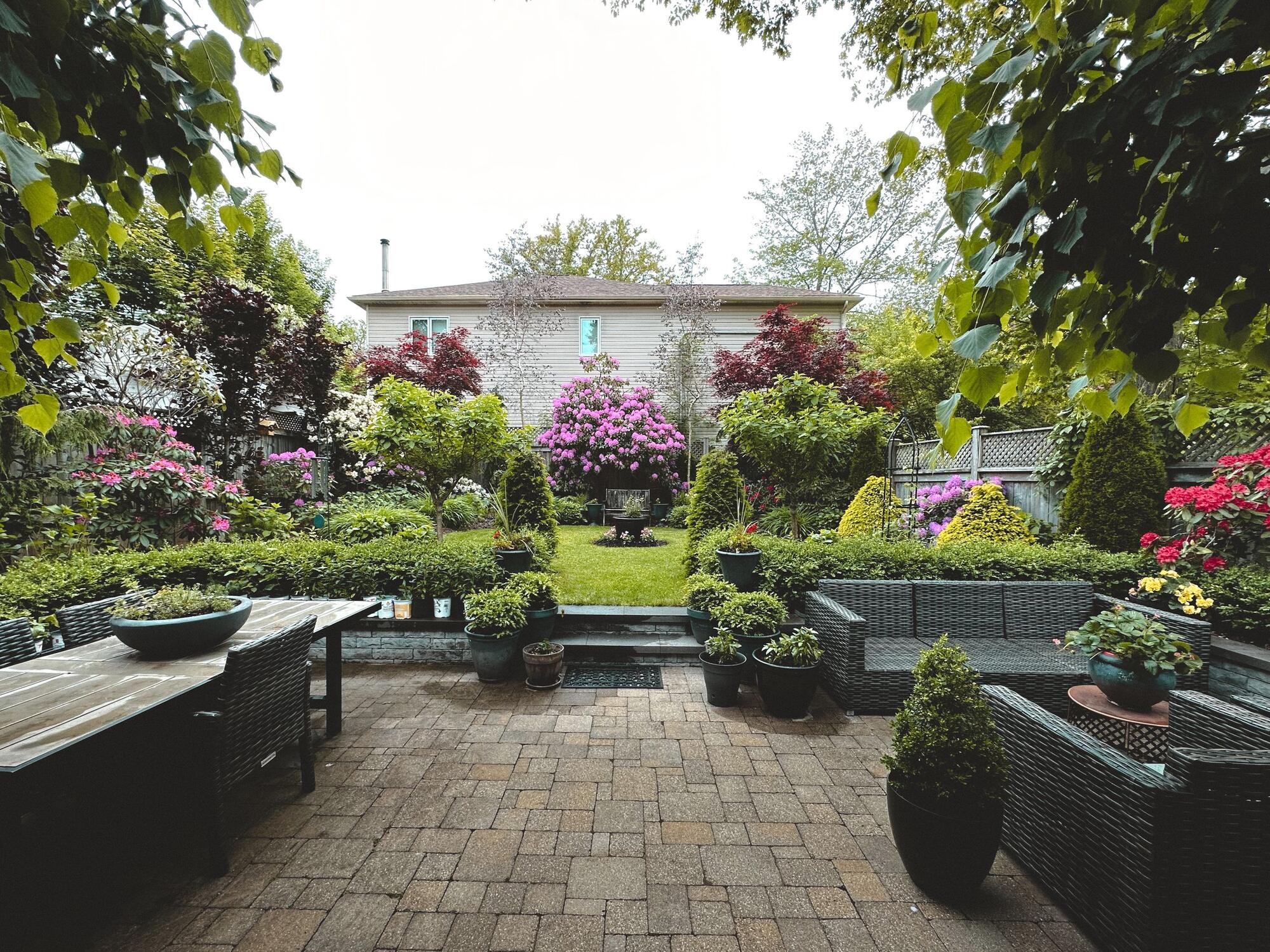 A lush shared backyard with a patio and garden behind a home